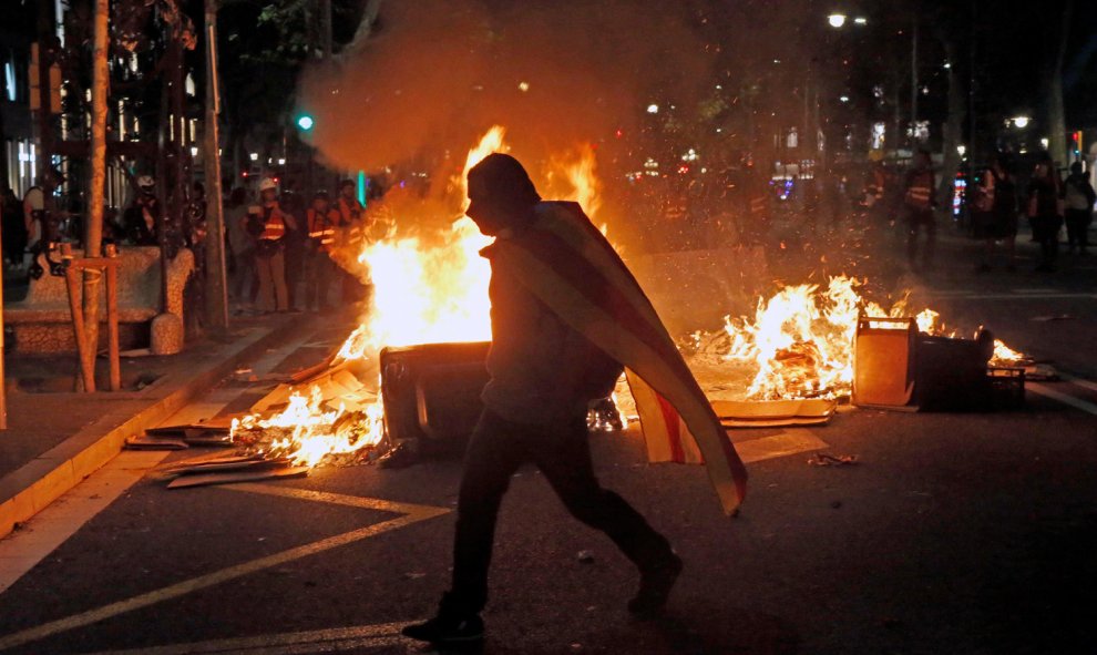 Un manifestante ante una barricada de fuego en Paseo de Gracia tras la concentración en la que miles de personas, convocadas por los denominados Comités de Defensa de la República (CDR), se han concentrado ante la Jefatura de la Policía Nacional de la Vi