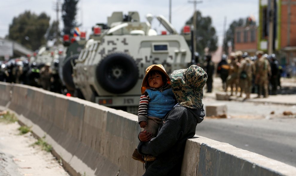 Una mujer sostiene a su hijo mientras los militares avanzan para atacar a los manifestantes contrarios al golpe de Estado en Bolivia, junto a la planta gasística de Sentaka, en El Alto, Bolivia.- REUTERS / DAVID MERCADO