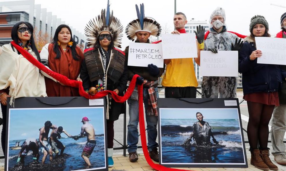 Activistas y líderes indígenas de 350.org durante la protesta que han protagonizado este domingo ante la sede de Repsol de Méndez Álvaro, en Madrid, para protestar contra la contaminación por petróleo y la industria de combustibles fósiles en Brasil. EFE/