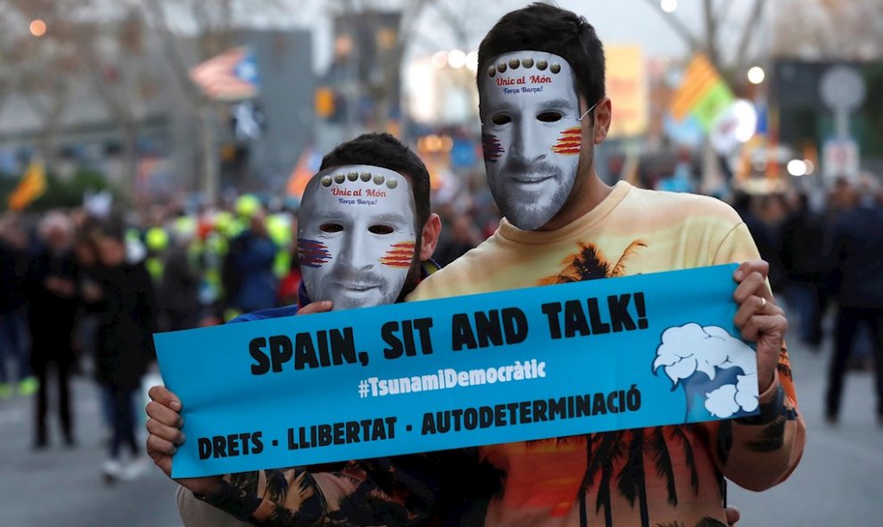 18/12/2019.- Dos manifestantes con caretas del futbolista Messi en los aledaños del Camp Nou, / EFE - TONI ALBIR
