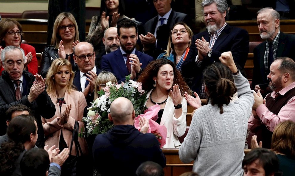 a diputada del grupo de Unidas Podemos Aina Vidal (c), que hoy ha asistido a votar a pesar de estar enferma de cáncer, recibe un ramo de flores de sus compañeros al término de la segunda y definitiva votación./ Mariscal (EFE)