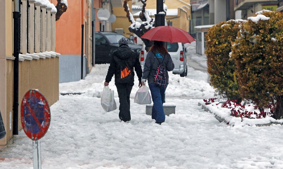 20/01/2020.- Dos pesonas caminan por una calle de la localidad alicantina de Castalla que amanecía hoy cubierta de nieve por el temporal Gloria que afecta a gran parte de la península. EFE/Morell