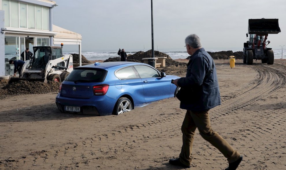 23/01/2020.- Un coche enterrado en la playa de de la Malvarrosa, en València, donde han comenzado las labores de limpieza tras el paso de la borrasca Gloria. / EFE - ANA ESCOBAR