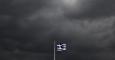 La bandera griega ondea sobre la Acrópolis de Atenas, bajo un cielo cubierto de nubes de tormenta. REUTERS/Yannis Behrakis
