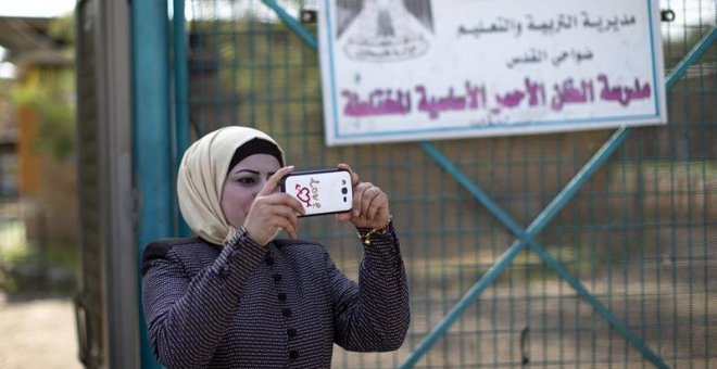 Una mujer hace una foto en el colegio de la comunidad de Jan al Ahmar. EFE/Atef Safadi