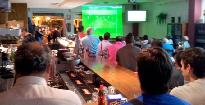 Clientes de un bar viendo un partido de fútbol por televisión.