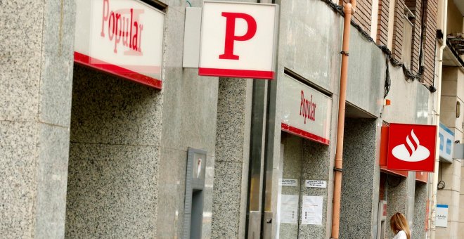 Una mujer usa un cajero automático en una oficina del Banco Santander junto a una sucursal del Banco Popular. REUTERS/Albert Gea