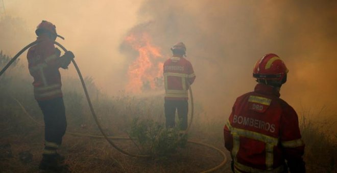 Tres bomberos trabajan para apagar las llamas en el bosque de Capelo, cerca de Gois. | RAFAEL MARCHANTE (EFE)