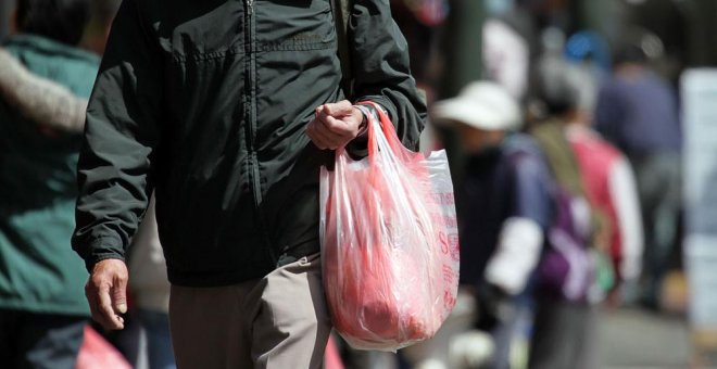 Un hombre carga una bolsa de plástico con la compra. AFP