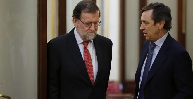 El presidente del Gobierno, Mariano Rajoy (i), conversa con el portavoz del PP en el Congreso, Rafael Hernando, en los pasillos de la Cámara Baja. /EFE