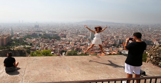 Una joven turista salta,mientras le toman una foto con el 'skyline' de Barcelona a su fondo. REUTERS/Albert Gea