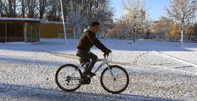 Un hombre se desplaza en bicicleta en medio del temporal de frío y nieve que afecta a León. / EFE