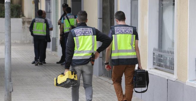 Agentes de la Policía trabajan ante la vivienda de Xàtiva donde la mujer fue asesinada. EFE/Natxo Francés