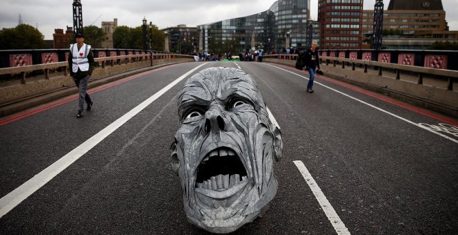 Los activistas ecologistas dejan en mitad del Puente Lambeth (Londres) la escultura de un rostro con cara de dolor. REUTERS