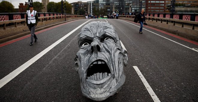 Los activistas ecologistas dejan en mitad del Puente Lambeth (Londres) la escultura de un rostro con cara de dolor. REUTERS