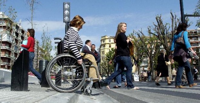 Imagen de archivo de una mujer en silla de ruedas cruzando una calle.