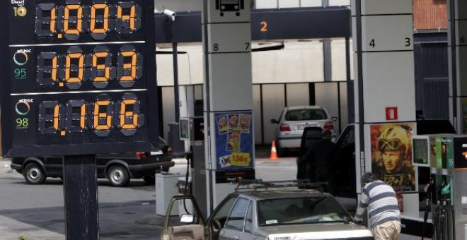 Un hombre reposta carburante en su coche en una estación de servicio.