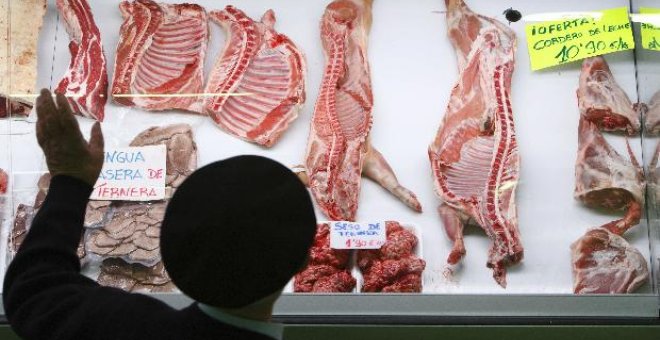 Un hombre observa cordero en el escaparate de una carnicería en el mercado de Vitoria.