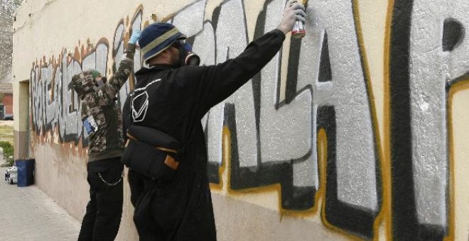 Dos grafiteros participan en la decoración de la fachada de una parroquia madrileña.