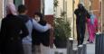 Un policía pasa junto a varios vecinos de la barriada de El Príncipe, donde la Policía española ha detenido esta madrugada a cuatro presuntos yihadistas, que, según el ministro del Interior, son dos parejas de hermanos "fuertemente radicalizados", muy adi