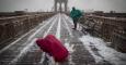 Dos turistas atraviesan el puente de Brooklyn en medio de la nevada. EFE/Andrew Kelly