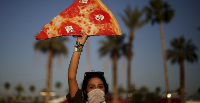 La pizza, alimento de los festivales en el Coachella. Una mujer posa con una réplica gigante.