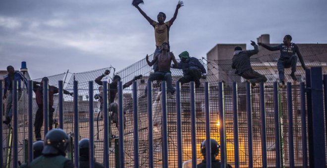 Inmigrantes subsaharianos encaramados a la valla de Melilla.- AFP