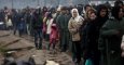 Refugiados y migrantes guardan cola bajo la lluvia para recibir una taza de café o té mientras esperan en un campo de refugiados cerca de Idomeni (Grecia). - EFE