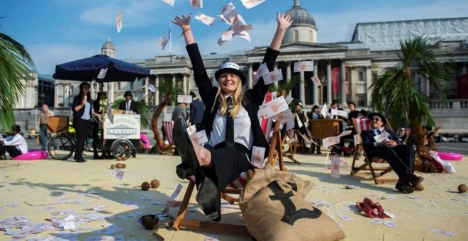 Una mujer lanza billetes al aire en una protesta contra los paraísos fiscales en la plaza Trafalgar de Londres. EFE/Hannah Mckay