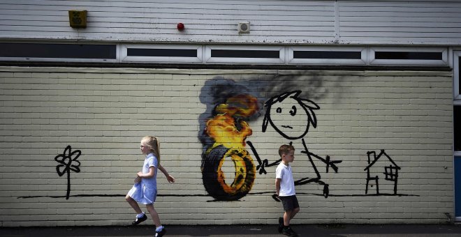 Niños frente a un graffiti del artista Banksy pintado en el exterior de un aula de la Escuela Primaria Bridge Farm en Bristol, Reino Unido.  REUTERS/Dylan Martinez