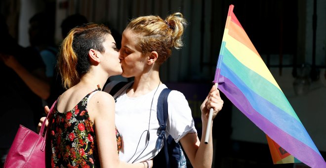 Dos participantesen la marcha en Estambul por los derechos de los transexuales en LGBT se besan sosteniendo una bandera arcoiris. REUTERS/Osman Orsal