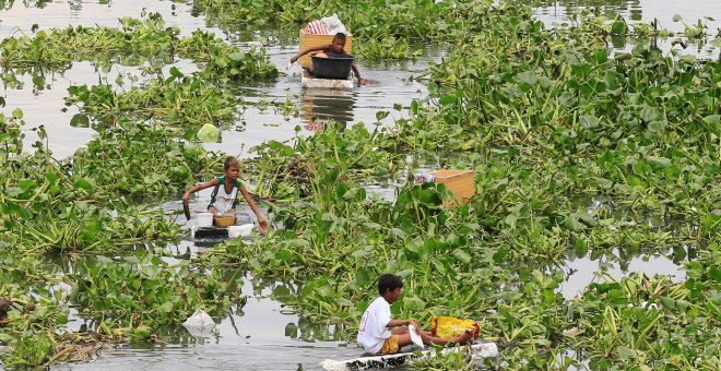 Niños filipinos atraviesan un río contaminado con barcas hechas por ellos mismos para recolectar elementos reutilizables en Manila, Filipinas/REUTERS
