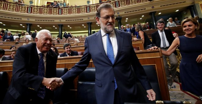 El presidente el Gobierno en funciones, Mariano Rajoy, se da un apretón de manos con Garcia-Margallo antes del debate de investidura en el Congreso de los Diputados. REUTERS/Juan Medina