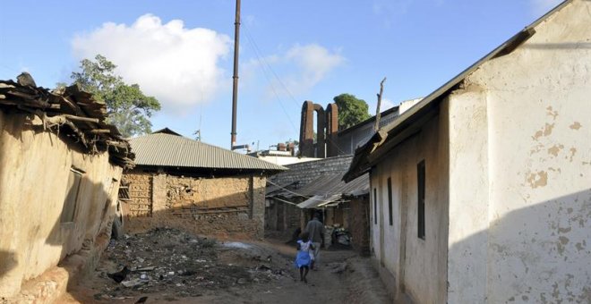 Una niña camina por las calles del poblado chabolista de Owino Uhuru, en Mombasa (Kenia), cuyos habitantes han demandado al Gobierno por permitir la actividad de una fábrica ilegal levantada entre sus viviendas (al fondo) que emitía vertidos de plomo.- EF