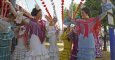 Jóvenes vestidas con el traje típico de flamenca bailan sevillanas en el Real de la Feria de Abril de la capital hispalense. EFE/Archivo