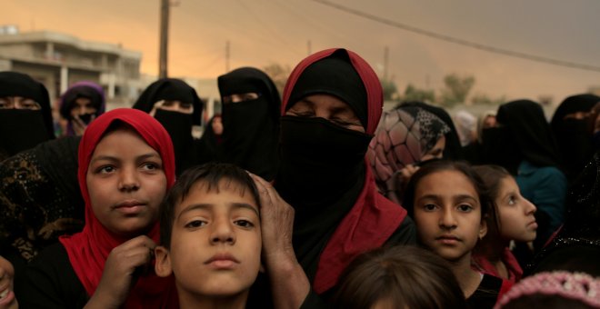 Refugiados hacen cola junto a las controles antes de ser evacuados de la 'Jungla' de Calais.  REUTERS/Philippe Wojazer