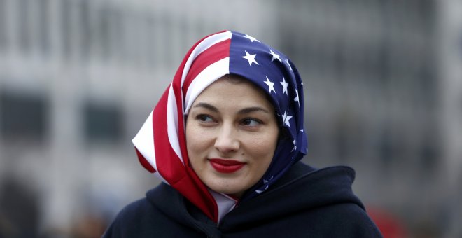 Una mujer musulmana con un velo con la bandera de Estados Unidos en la concentración contra Trump en Berlín / REUTERS