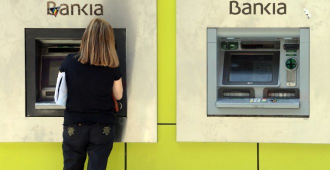 Una mujer opera en un cajero automático en una sucursal de Bankia en Madrid. AFP