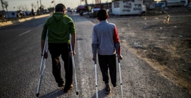 Dos niños sirios heridos pasean por un campamento de refugiados en Kilis, en el centro-sur de Turquía. - AFP