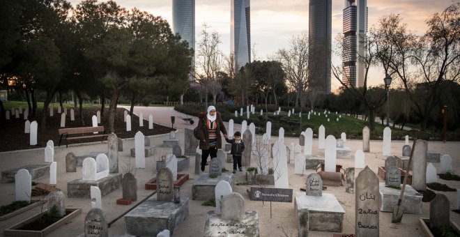 Una madre y su hijo observan el cementerio que Save the Children ha simulado en un parque de Madrid para recordar que, en Siria, han muerto 16.000 niños desde que comenzó la guerra, hace seis años. PEDRO ARMESTRE / SAVE THE CHILDREN