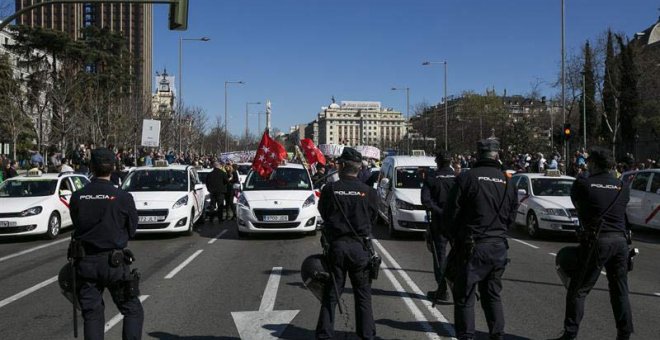 Agentes de la Policía Nacional vigilan durante la manifestación de los taxistas por el centro de Madrid. | SANTI DONAIRE (EFE)