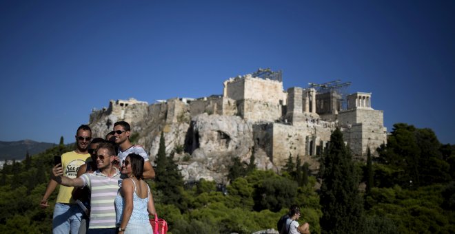 Unos turistas se toman un selfi desde la Colina de Ares, en Atenas, con la Acrópolis al fondo. REUTERS/Stoyan Nenov