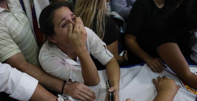 Amigos y familiares de Rodrigo Quintana, quien murió esta madrugada tras las protestas y disturbios de anoche en Asunción, se lamentan sobre el feretro.- EFE/Andrés Cristaldo Benítez