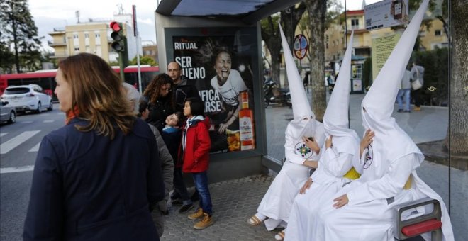 Unos nazarenos descansan en una parada de autobús en Sevilla. REUTERS/Marcelo del Pozo