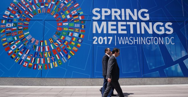 Unos peatones pasan por delante del mural que anuncia la reunión de primavera del FMI y del Banco Mundial en Washington. AFP/Mandel Ngan