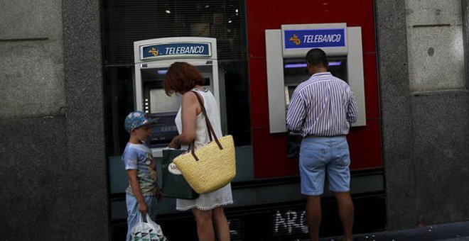 Un par de personas utilizan los cajeros de un banco en Madrid. EFE