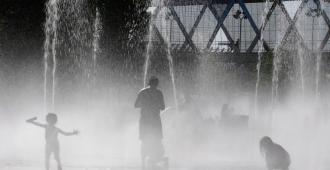 Unos niños se refrescan en unas fuentes cercanas al río Manzanares el julio pasado en Madrid. AFP