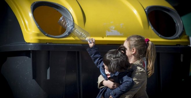 Una mujer recicla una botella de plástico en el contenedor amarillo. ECOEMBES