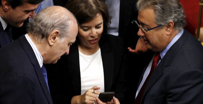 La vicepresidenta del Gobierno, Sorya Sáenz de Santamaría, conversa con el ministro del Interior, Juan Ignacio Zoido (d), y los diputados del PP Jorge Fernández Díaz (i) y José Luis Ayllón (2-i), durante un receso en el debate de las enmiendas a la totali