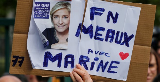 Un seguidor del Frente Nacional, sujeta una pancarta con la imagen de Marine Le Pen. REUTERS/Pascal Rossignol